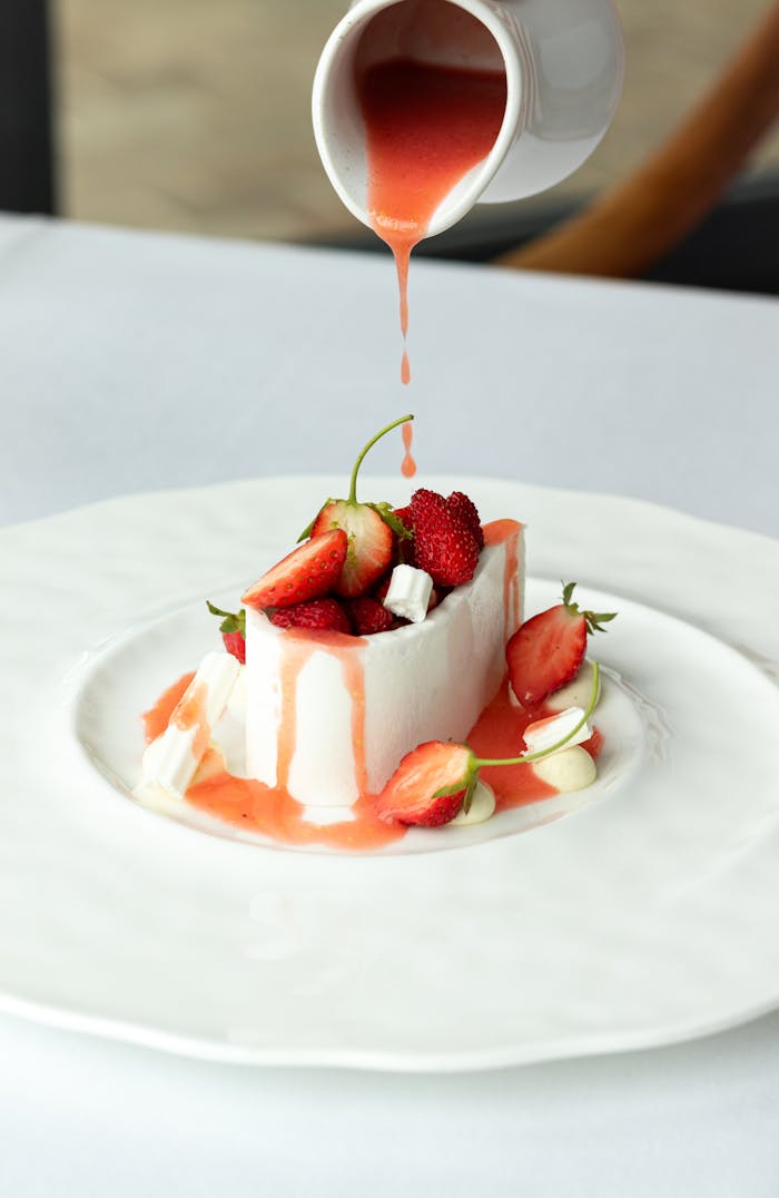 Indulge in a gourmet dessert with fresh strawberries and silky sauce in a French restaurant.